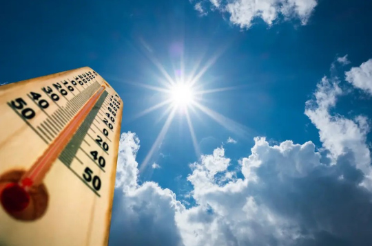 Ein blauer Himmel, mit strahlender Sonne und einem symbolischen Thermometer mit hohen Temperaturen im Bild. 