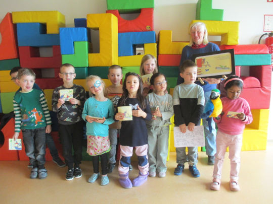 Eine gemischte Kindergruppe stehen vor bunten Polstern. Sie halten alle ein Käpt`n Kork Buch in den Händen.